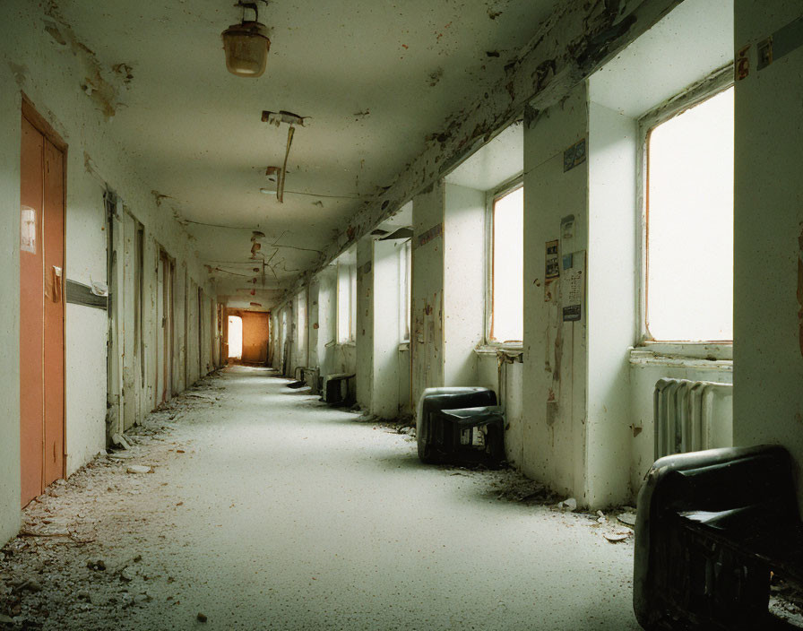 Desolate abandoned corridor with flaking paint and debris.