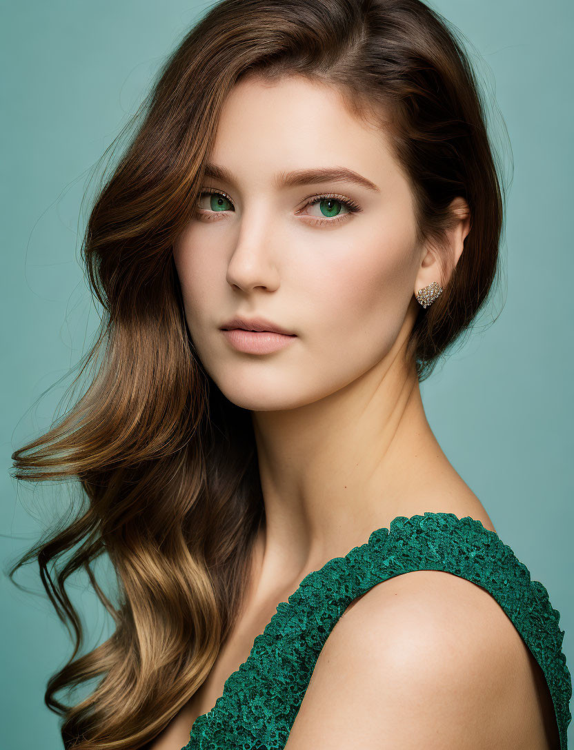 Woman with Long Wavy Brown Hair in Green Lace Dress on Teal Background