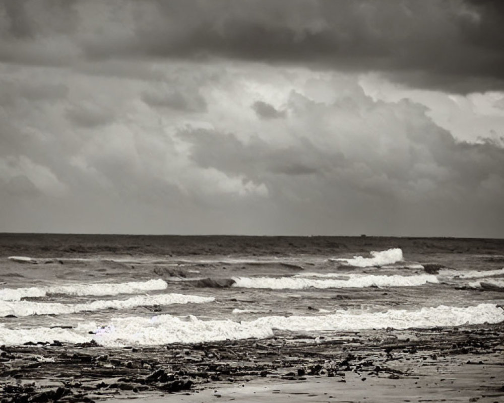 Stormy sea waves crashing on sandy shore under cloudy sky