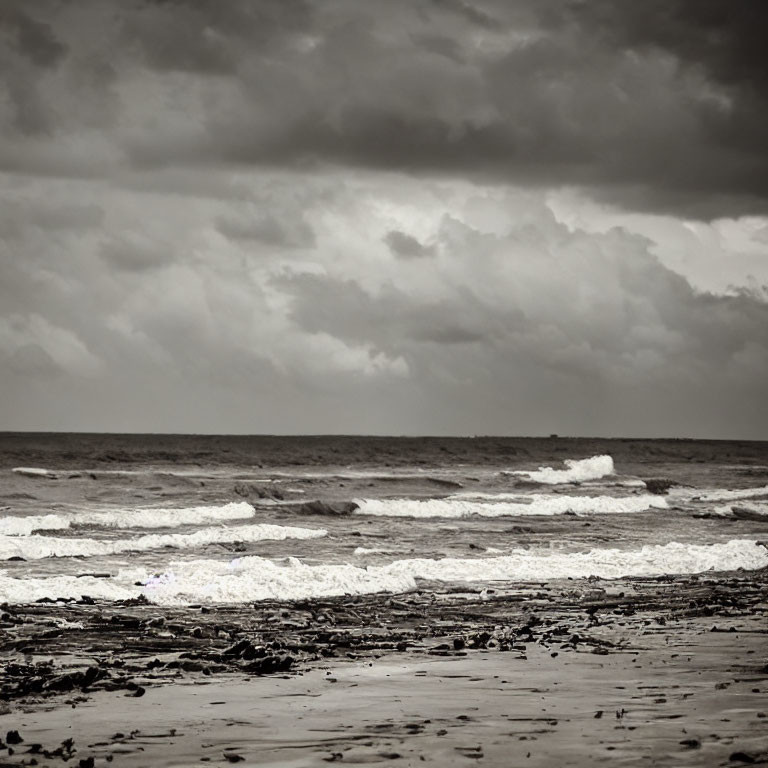 Stormy sea waves crashing on sandy shore under cloudy sky