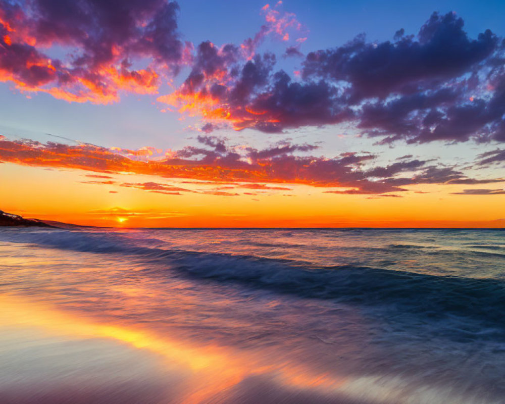 Colorful sunset reflecting on calm ocean with purple and orange clouds