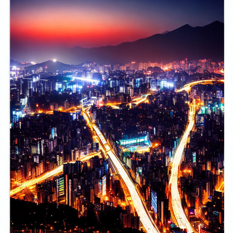 Twilight cityscape with illuminated streets, buildings, and mountains