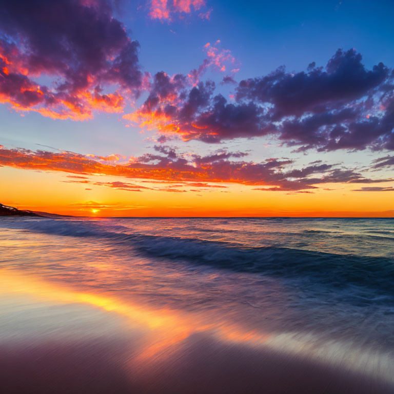 Colorful sunset reflecting on calm ocean with purple and orange clouds