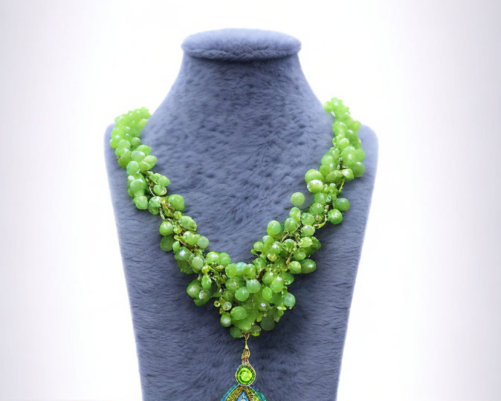 Green Beaded Necklace with Blue and Gold Peacock Pendant on Grey Mannequin