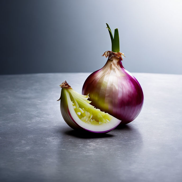 Fresh red onion whole and quarter slice with green shoots on grey textured surface.