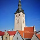 Historic tower and red-roofed buildings against blue sky in painting style