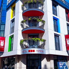 Colorful illustration of multi-storied building with flower-filled balconies under blue sky