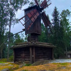 Colorful windmill surrounded by trees, wheat field, and house.