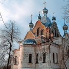 Gothic church with spires in snow, figures in red cloaks at dusk