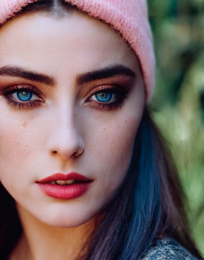 Close-up Portrait: Woman with Striking Blue Eyes in Pink Beanie, Nose Ring, and Styled