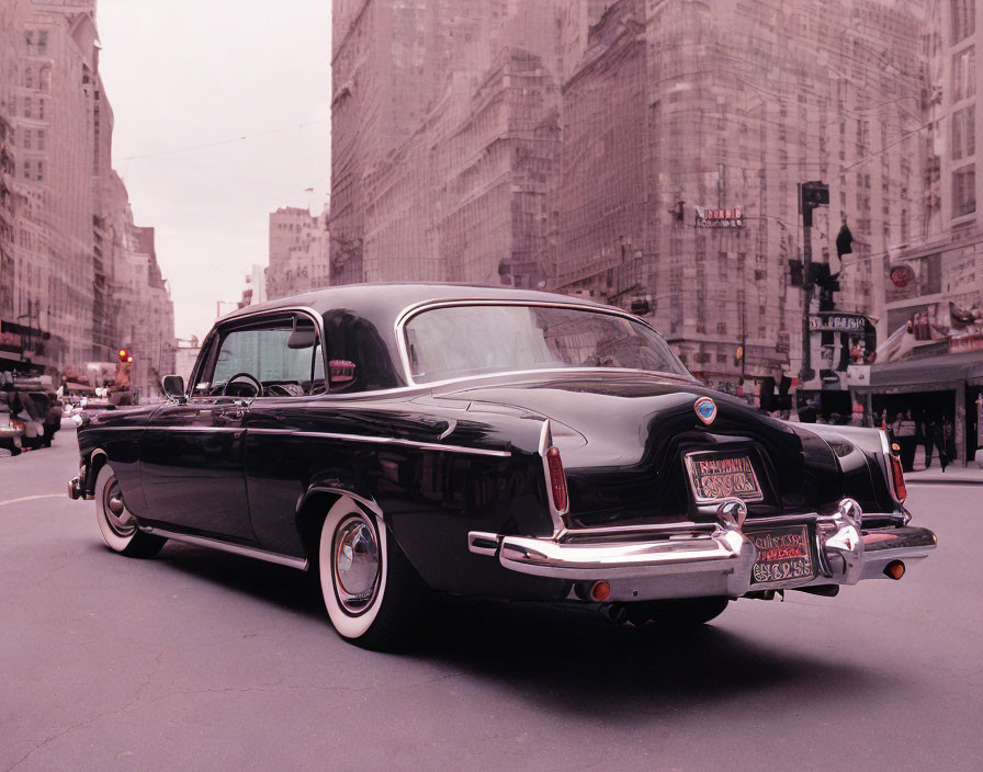 Vintage black car parked on city street with buildings and pinkish sky