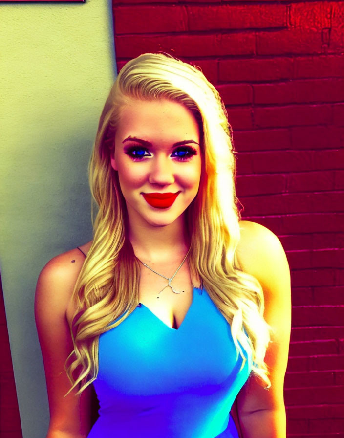 Blonde woman in blue dress with red lipstick against red wall