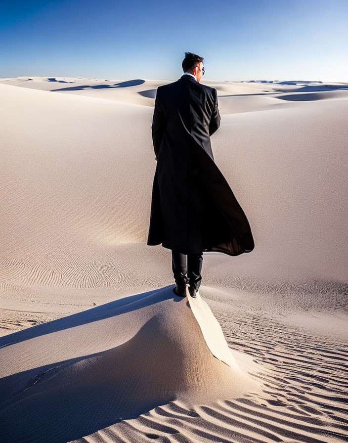 Person in Black Coat Standing on Sand Dune Under Clear Sky