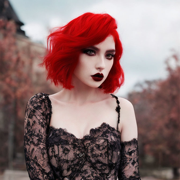 Red-haired person in dark makeup wearing black lace against autumn leaves.