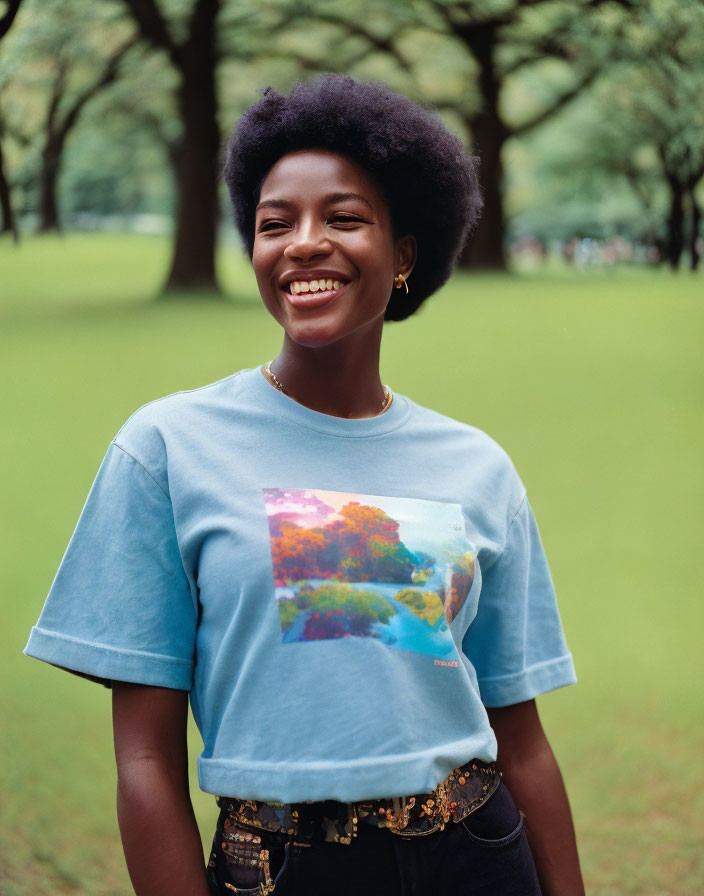 Smiling woman with afro in blue T-shirt outdoors