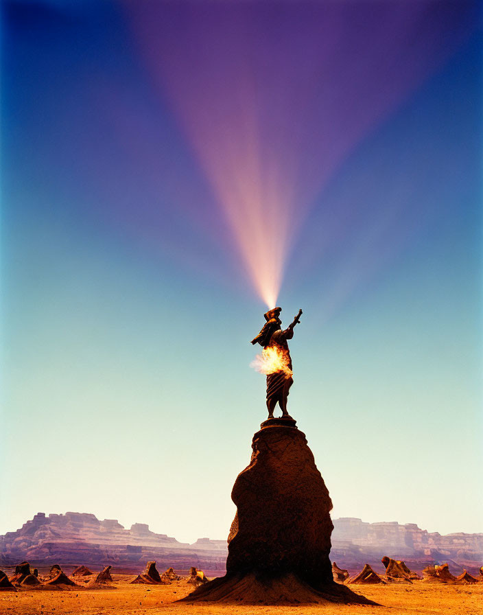 Silhouetted statue on rock pedestal under sunbeams and blue sky