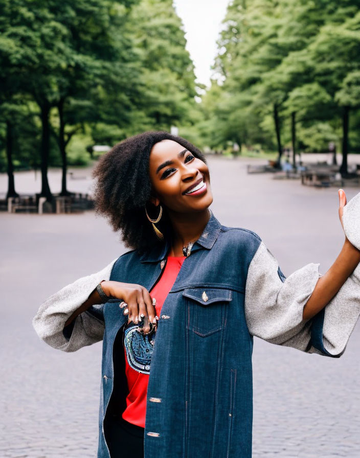 Smiling woman with afro hairstyle in denim jacket on park pathway