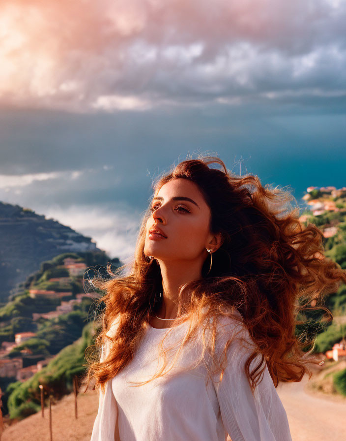 Woman with flowing hair against hills and dramatic sky