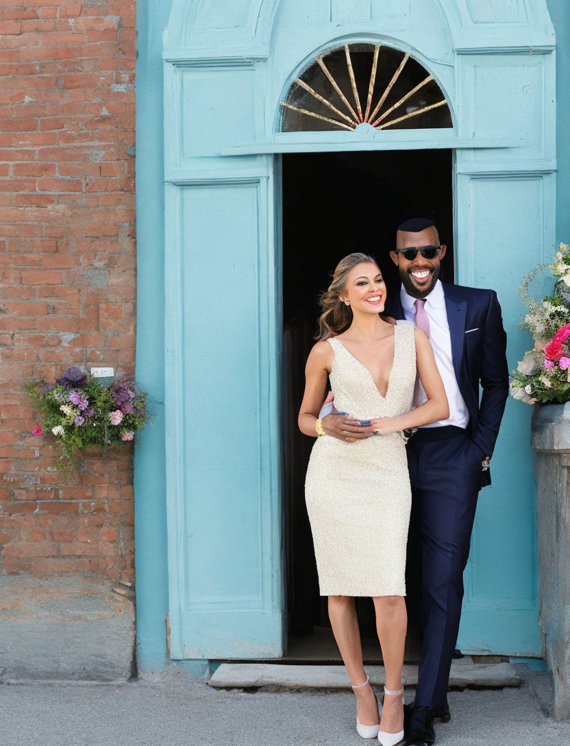 Elegant couple posing by teal door and brick wall