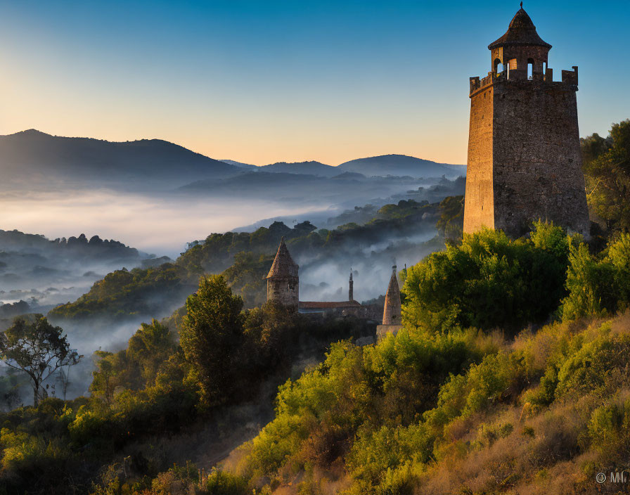 Medieval tower in misty dawn over foggy valley and forest landscape