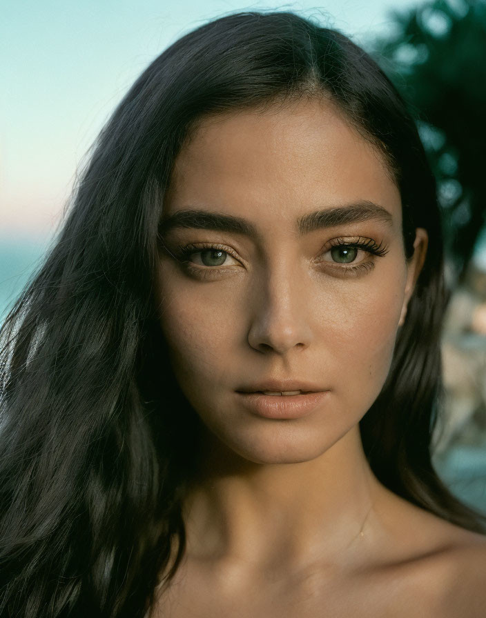 Portrait of woman with olive skin, dark hair, and green eyes in natural setting