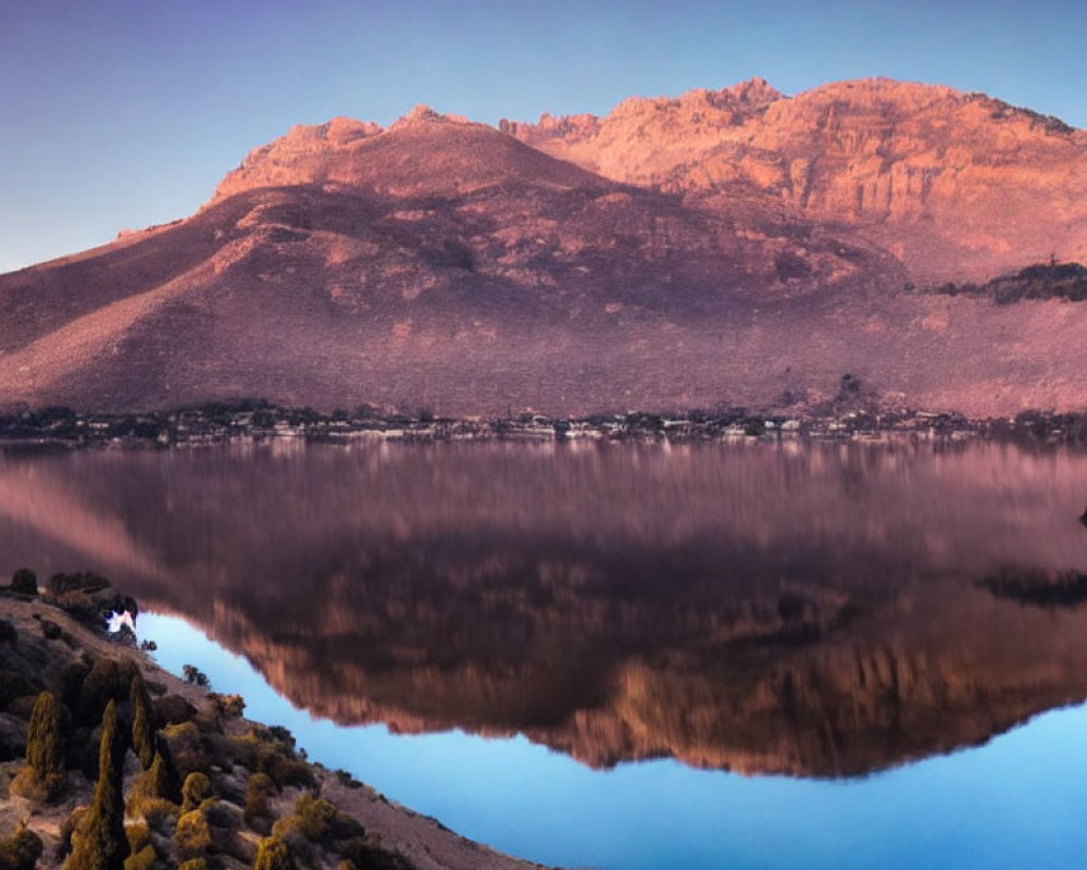 Mountain reflecting on still lake at dawn or dusk with serene purple and blue hues