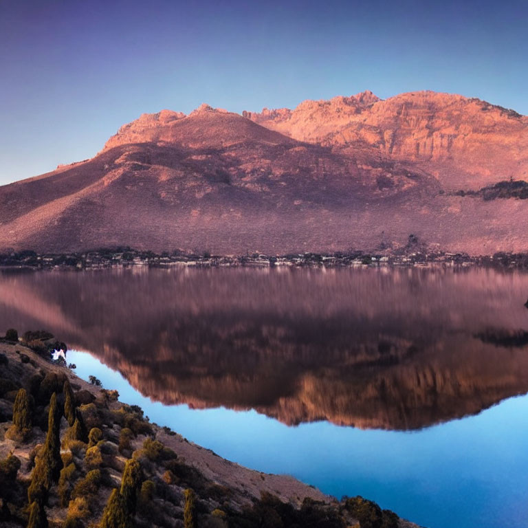 Mountain reflecting on still lake at dawn or dusk with serene purple and blue hues