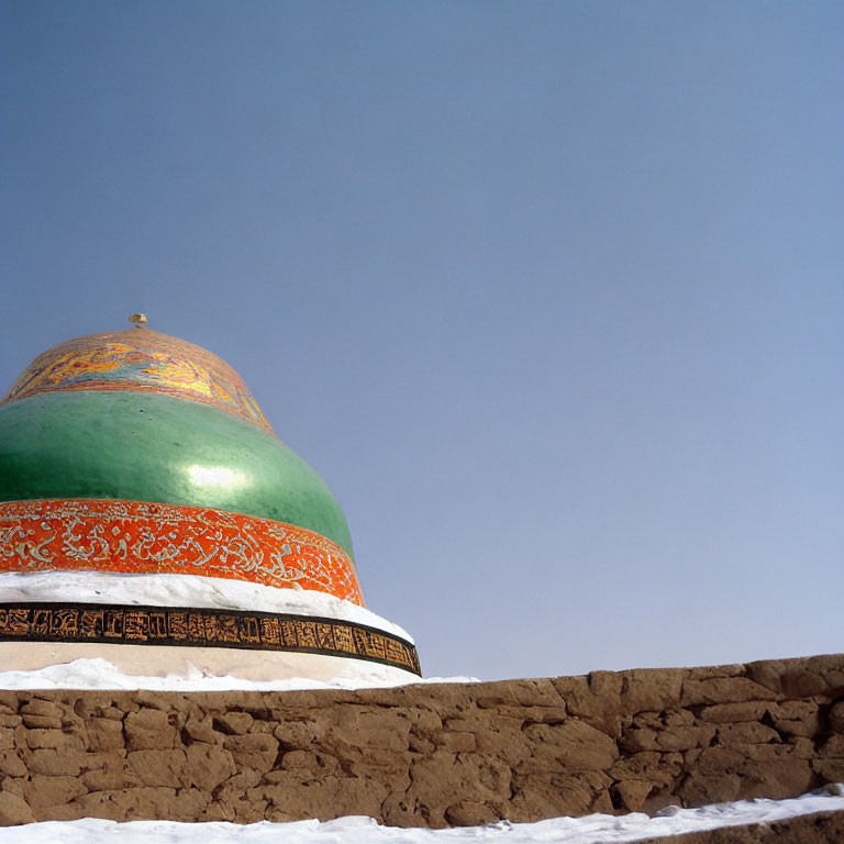 Green and Orange Patterned Dome Against Blue Sky with Snow-Covered Wall