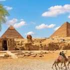 Ancient Egyptian Pyramids and Sphinx with camels and beetles in a clear blue sky