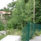 Abandoned overgrown ruin with mossy waterfall & remnants of vehicle