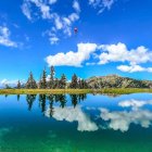 Tranquil lake reflects traditional buildings under blue sky