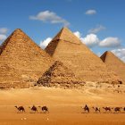 Ancient pyramids with capstones, camels, people, and shooting stars captured in a serene