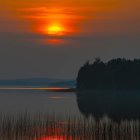 Vibrant sunset scene with UFOs, mountains, birds, and water