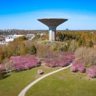 Surreal futuristic landscape with flying saucer structure on eroded pillars surrounded by green waters and pink