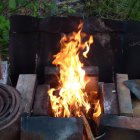 Group of people by bonfire near cabin at sunset in woods