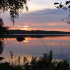 Scenic lake with boats, jetty, mountains, forest, and sunrise