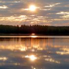 City skyline at sunset reflecting on calm river with warm glow.