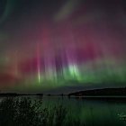 Pyramids by reflective water under vivid night sky with northern lights, comet, and futuristic aircrafts