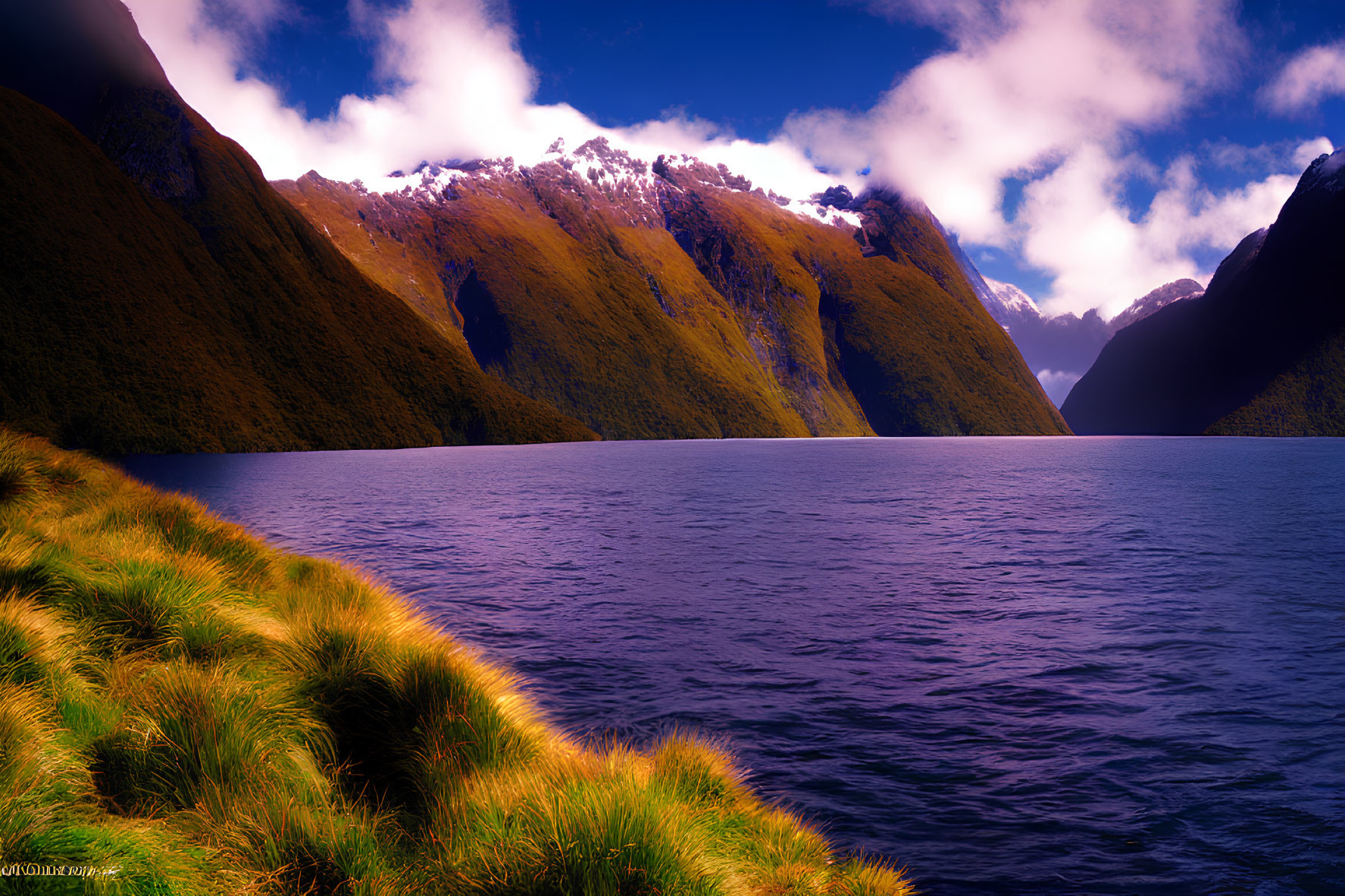 Tranquil lake with green hills, dynamic sky, and snowy peaks