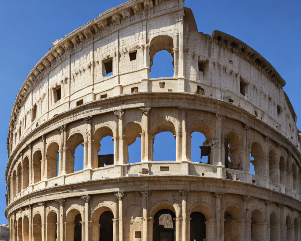 Daytime view of Ancient Roman Colosseum with arched exterior and clear blue sky