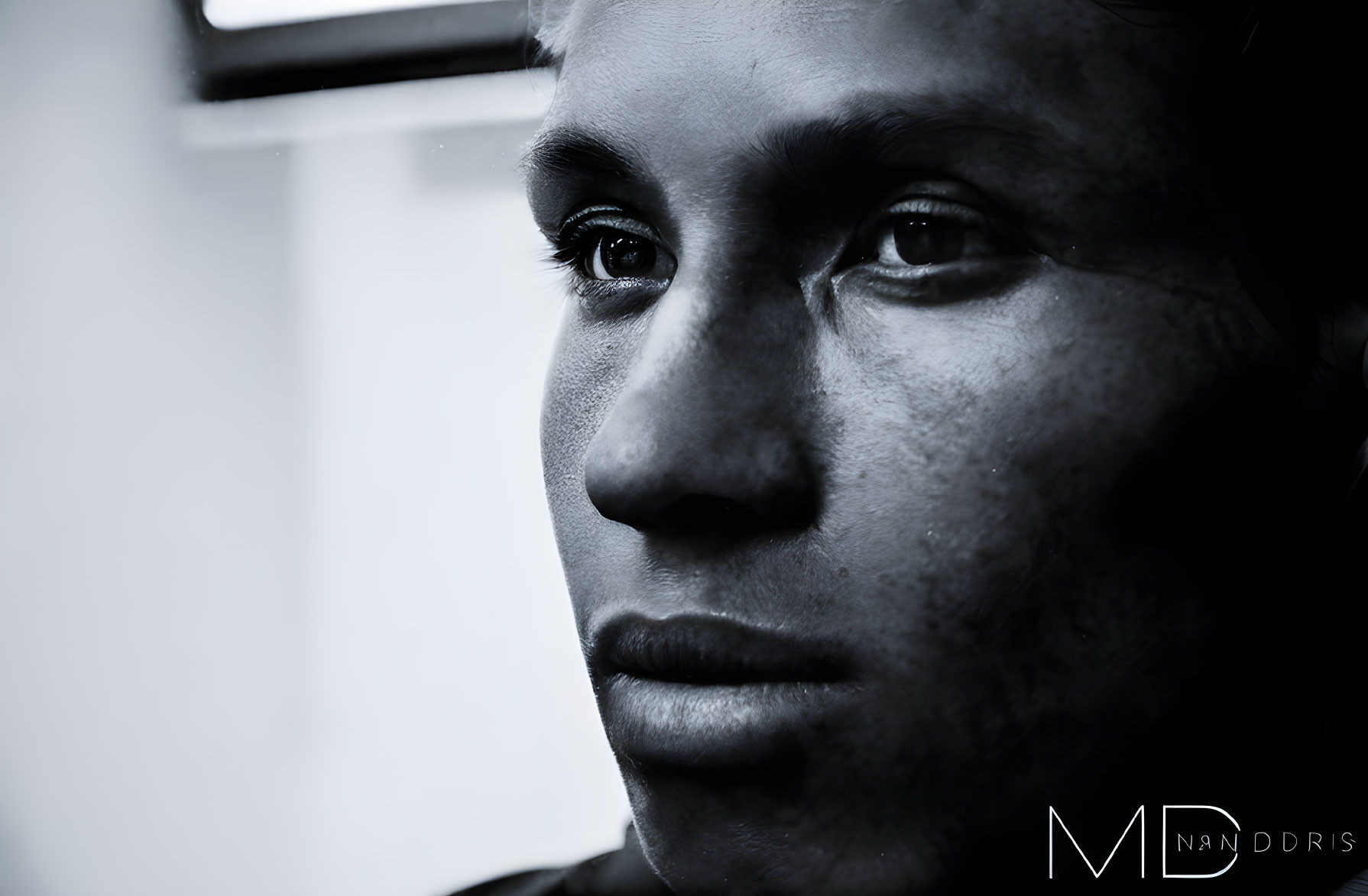 Monochrome close-up of a person's eye, nose, and lips with a pensive expression