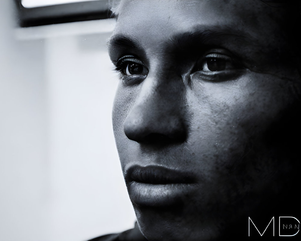 Monochrome close-up of a person's eye, nose, and lips with a pensive expression