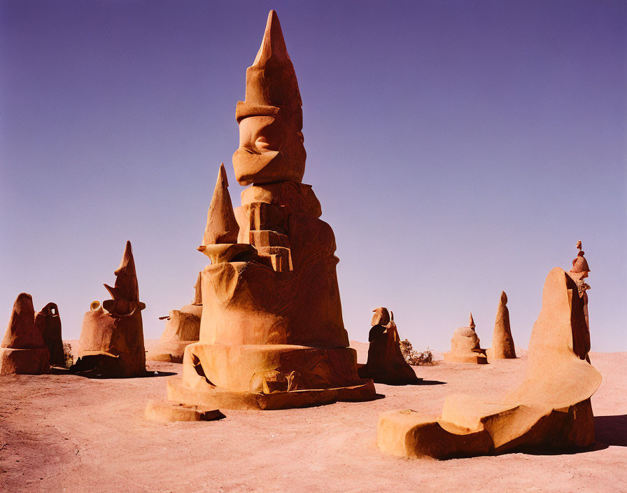 Surreal desert landscape with slender rock formations under clear blue sky