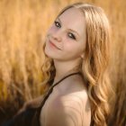 Young girl with light hair surrounded by butterflies in a golden grass field