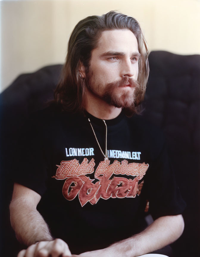 Bearded man in black t-shirt with colorful lettering gazes sideways