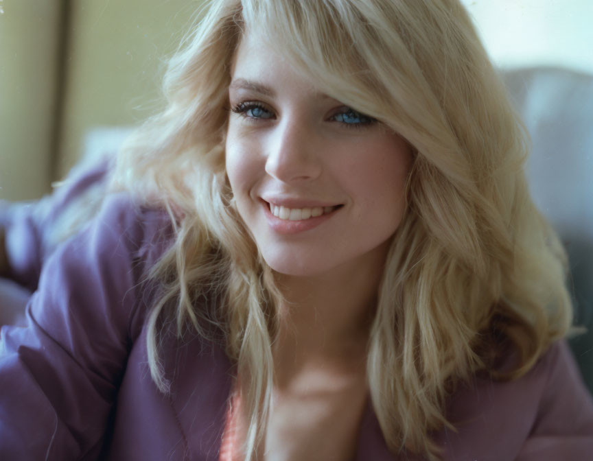 Blonde woman in purple top smiling at camera