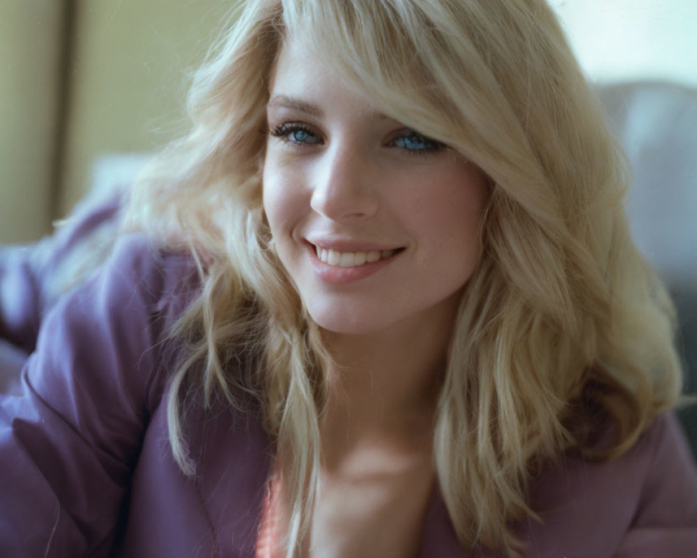 Blonde woman in purple top smiling at camera