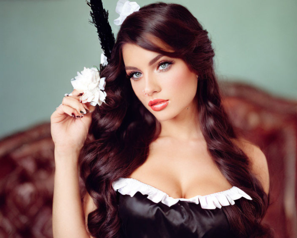 Woman with wavy hair in vintage dress holding white flower in classic interior.