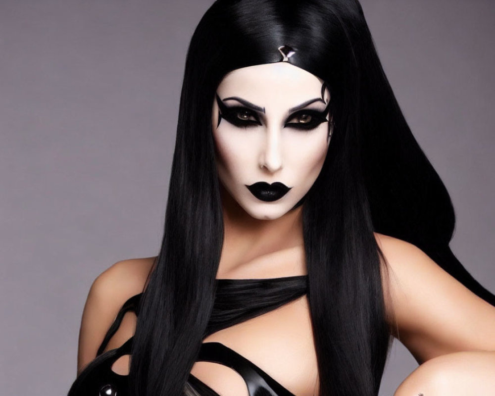 Dramatic black and white makeup with long black hair and dark attire on grey background