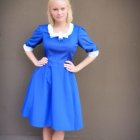 Vintage-style woman in blue dress with white collar and gloves on speckled backdrop